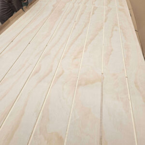 U-groove plywood sheets with visible wood grain in a workshop.